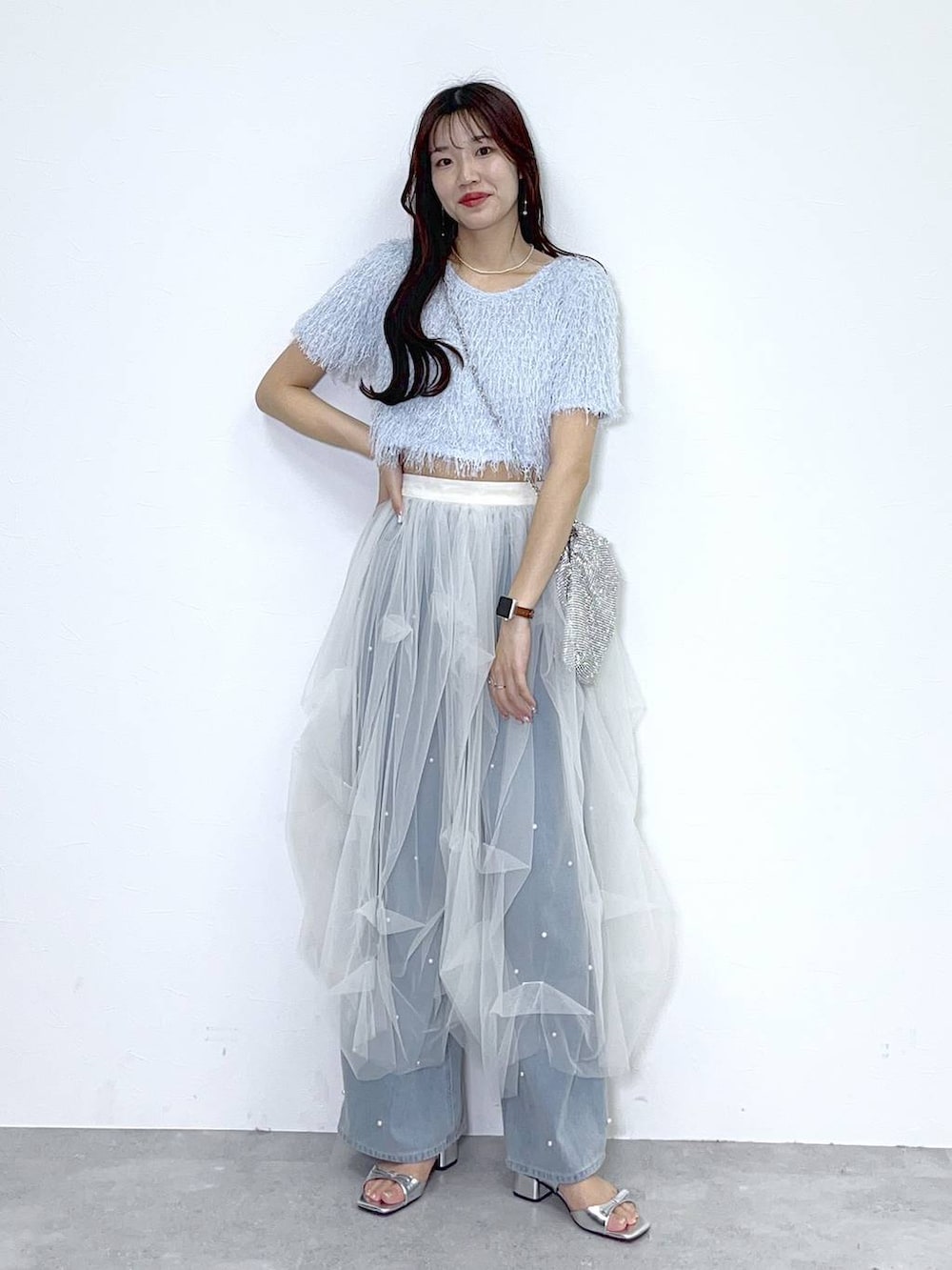 シルバー系のショルダーバッグ、ブルー系のデニムパンツ、ホワイト系のキャミソールを着用したレディースの春コーディネートの2枚目の写真