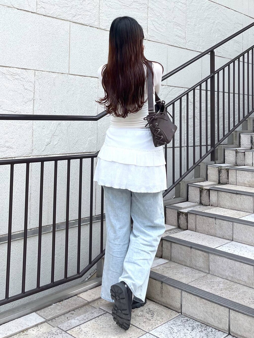 ブルー系のデニムパンツ、ホワイト系のキャミソール、ホワイト系のスカートを着用したレディースの春コーディネートの5枚目の写真
