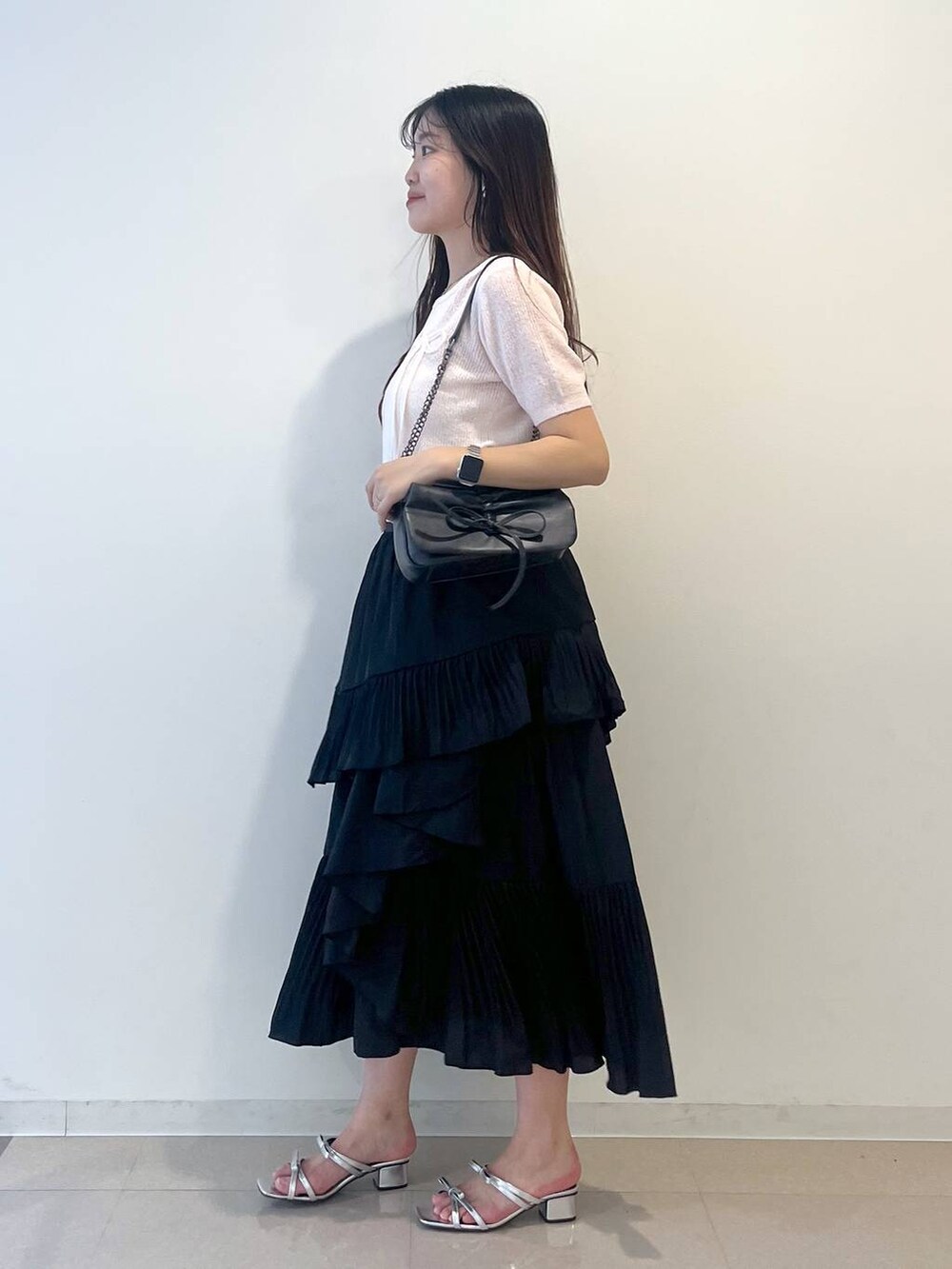 グレー系のショルダーバッグ、ホワイト系のキャミソール、ブラック系のスカートを着用したレディースの春コーディネートの3枚目の写真