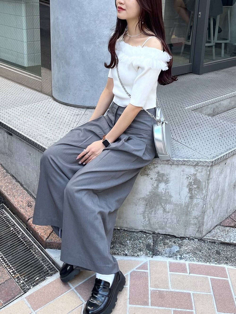 シルバー系のショルダーバッグ、グレー系のスラックス、ホワイト系のキャミソールを着用したレディースの夏コーディネートの5枚目の写真