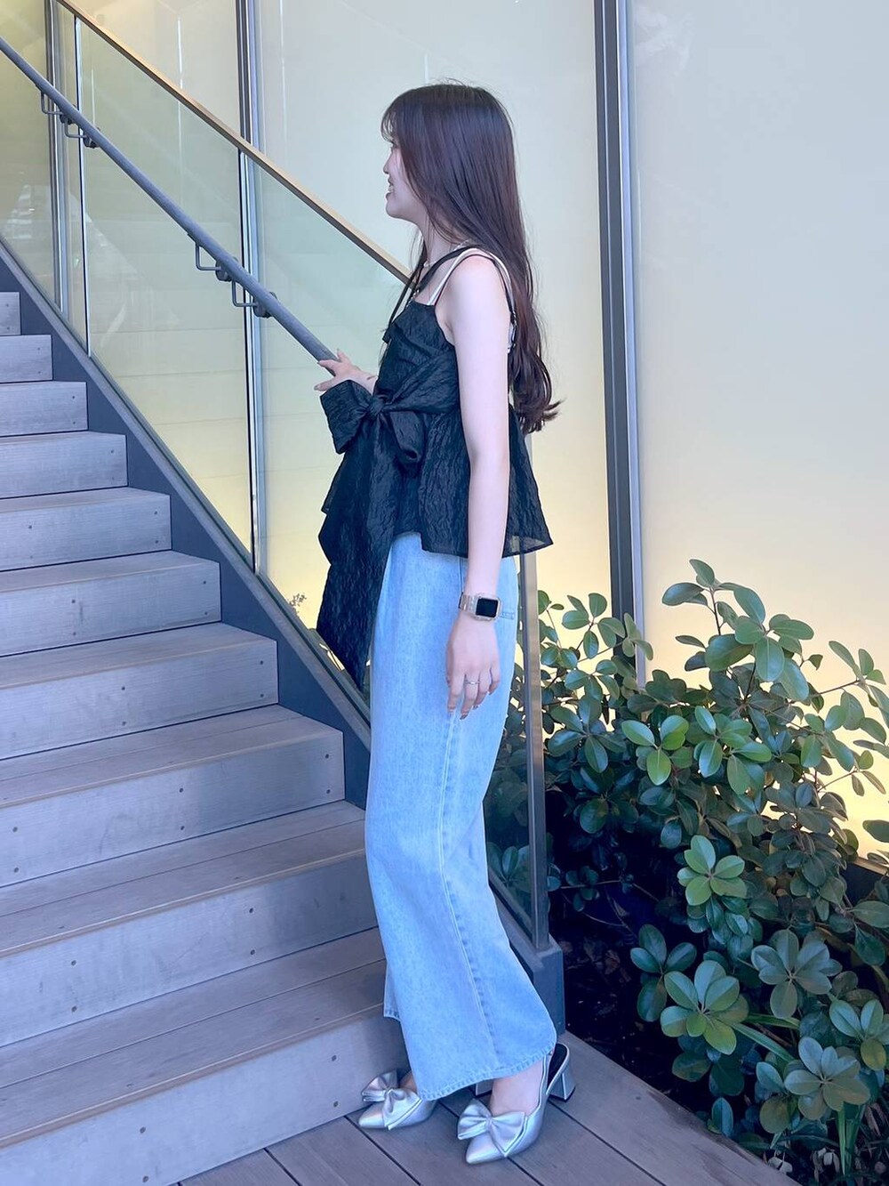 シルバー系のサンダル、ブラック系のショルダーバッグ、ホワイト系のキャミソールを着用したレディースの夏コーディネートの2枚目の写真