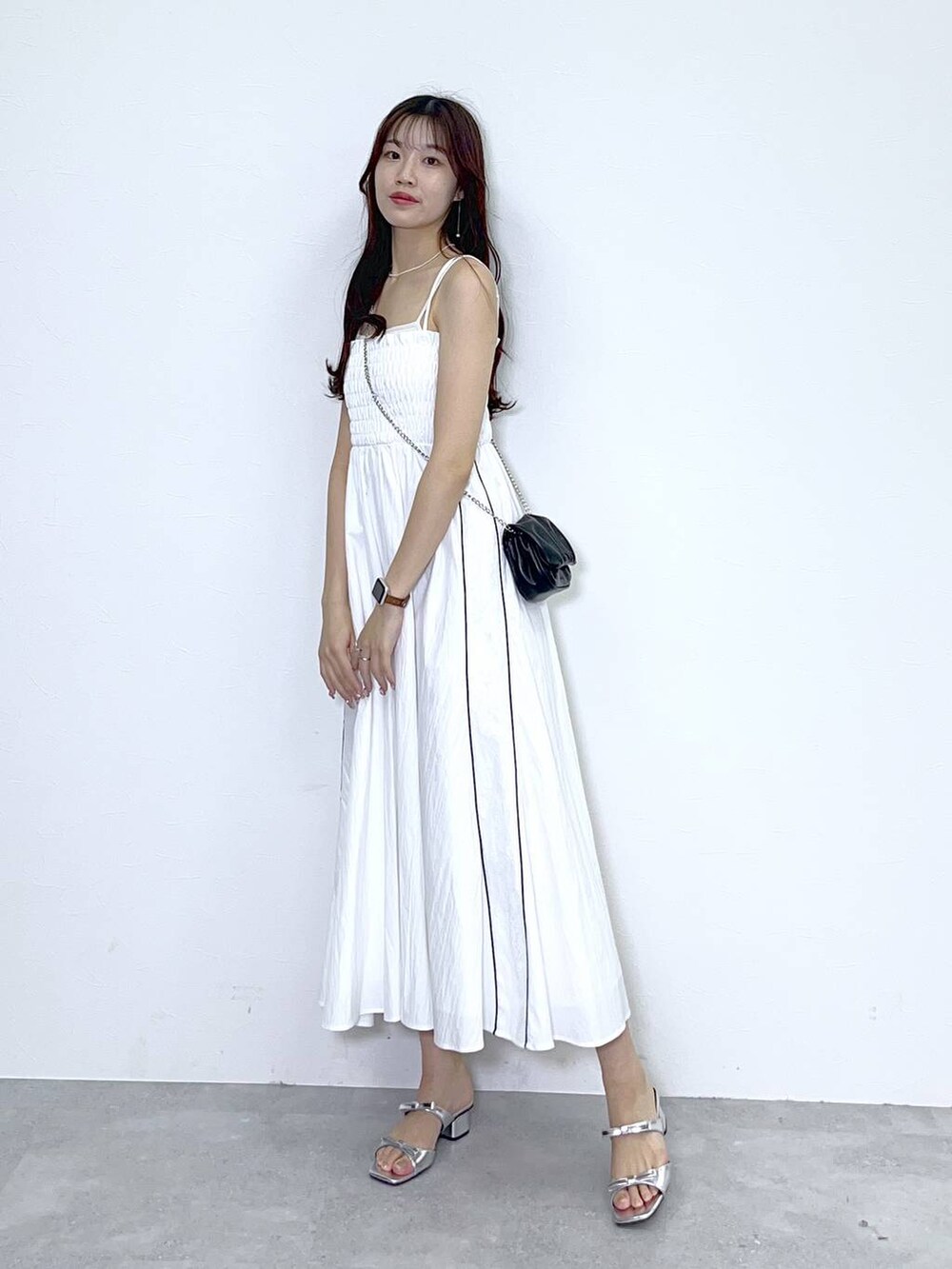 ブラック系のショルダーバッグ、シルバー系のサンダル、ホワイト系のワンピースを着用したレディースの夏コーディネートの5枚目の写真