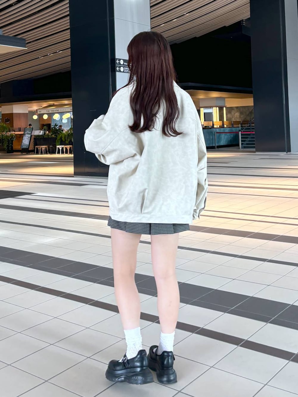 ブラック系のスニーカー、ホワイト系のキャミソール、ホワイト系のブルゾンを着用したレディースの秋コーディネートの3枚目の写真