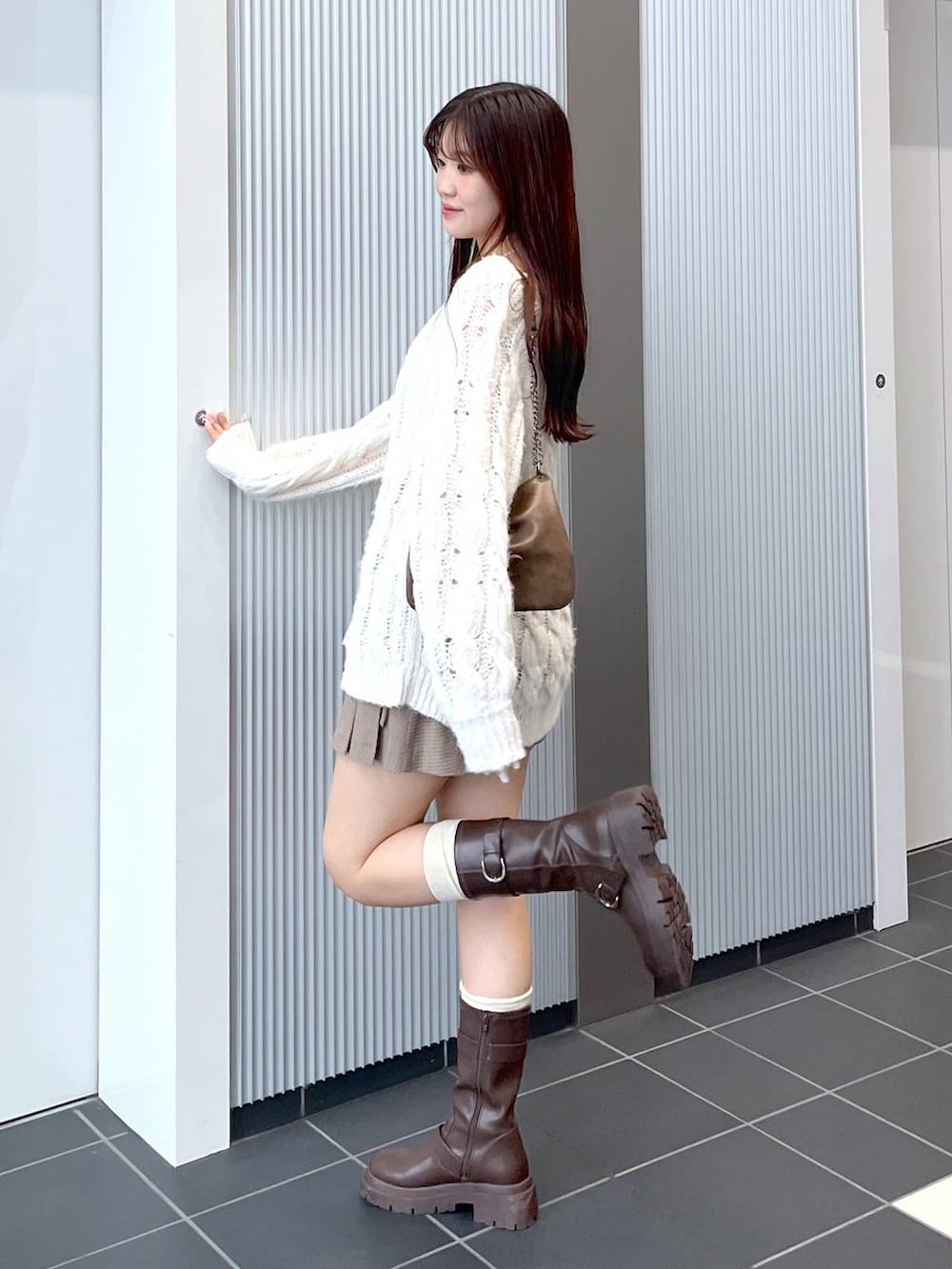 ブラウン系のショルダーバッグ、ブラウン系のブーツ、ホワイト系のキャミソールを着用したレディースの秋コーディネートの2枚目の写真