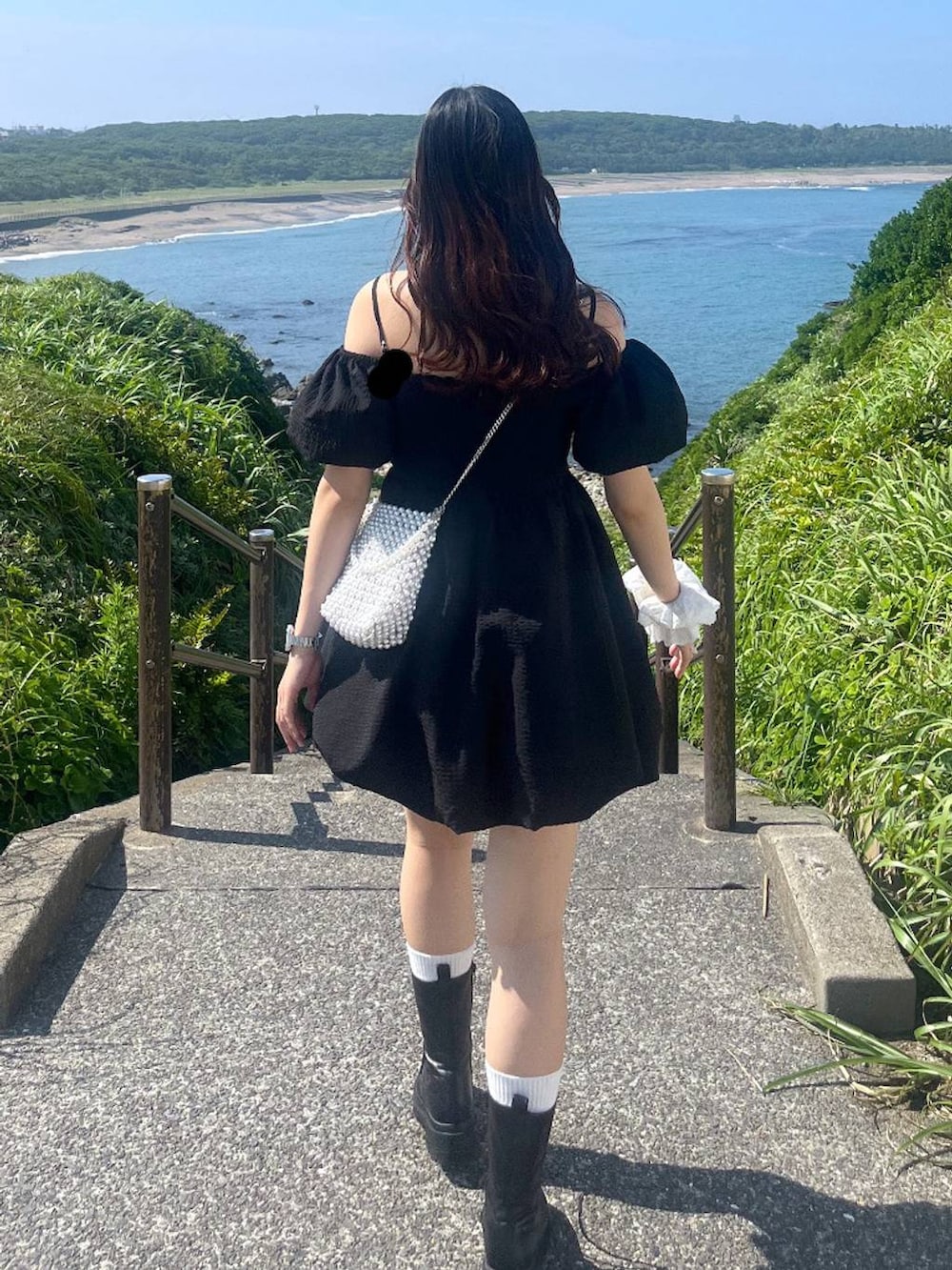 ホワイト系のキャミソール、ブラック系のワンピース、ブラック系のブーツを着用したレディースの夏コーディネートの6枚目の写真