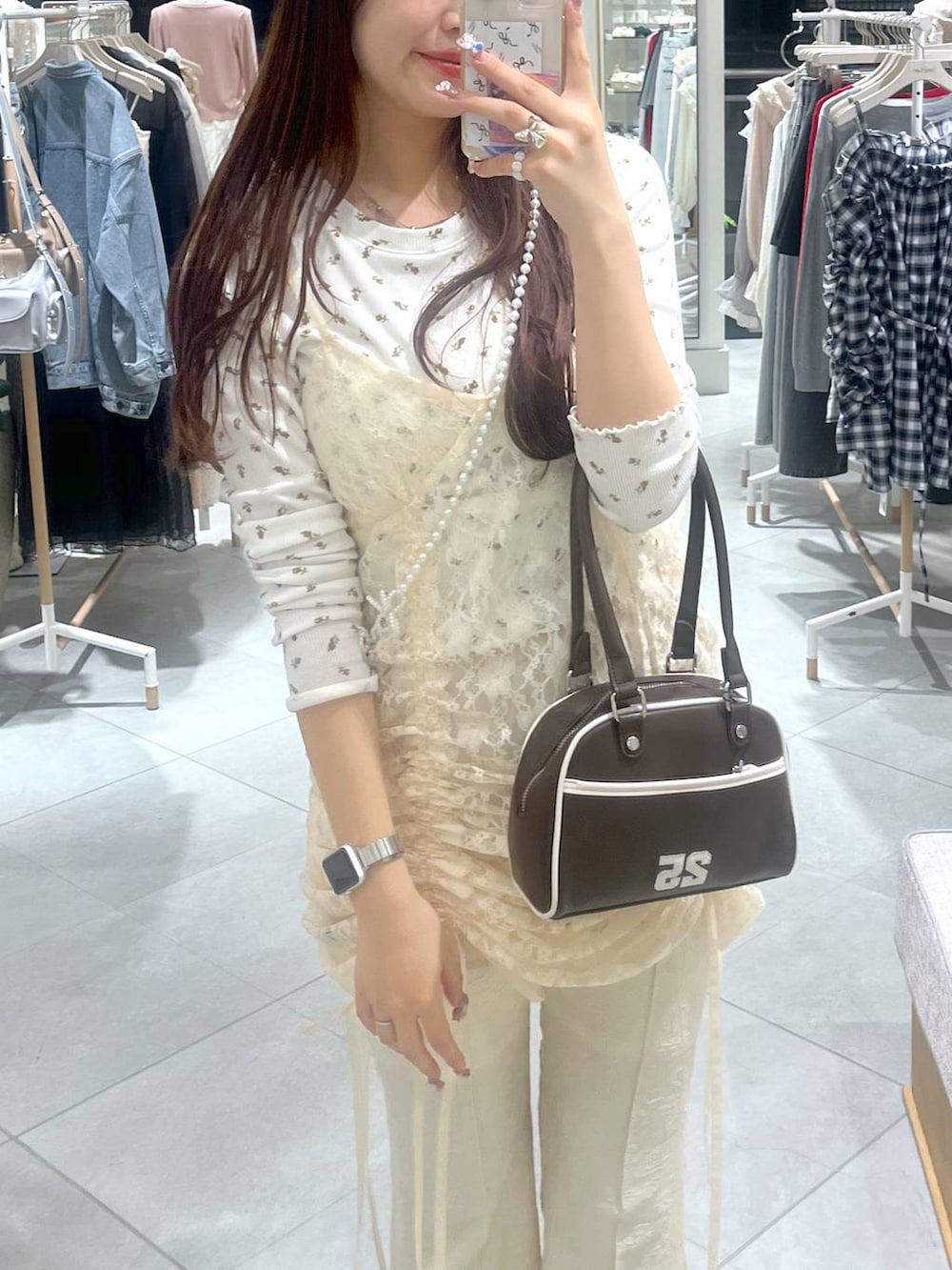 ベージュ系のワンピース、ブラウン系のボストンバッグ、ホワイト系のスマホグッズを着用したレディースの春コーディネートの5枚目の写真