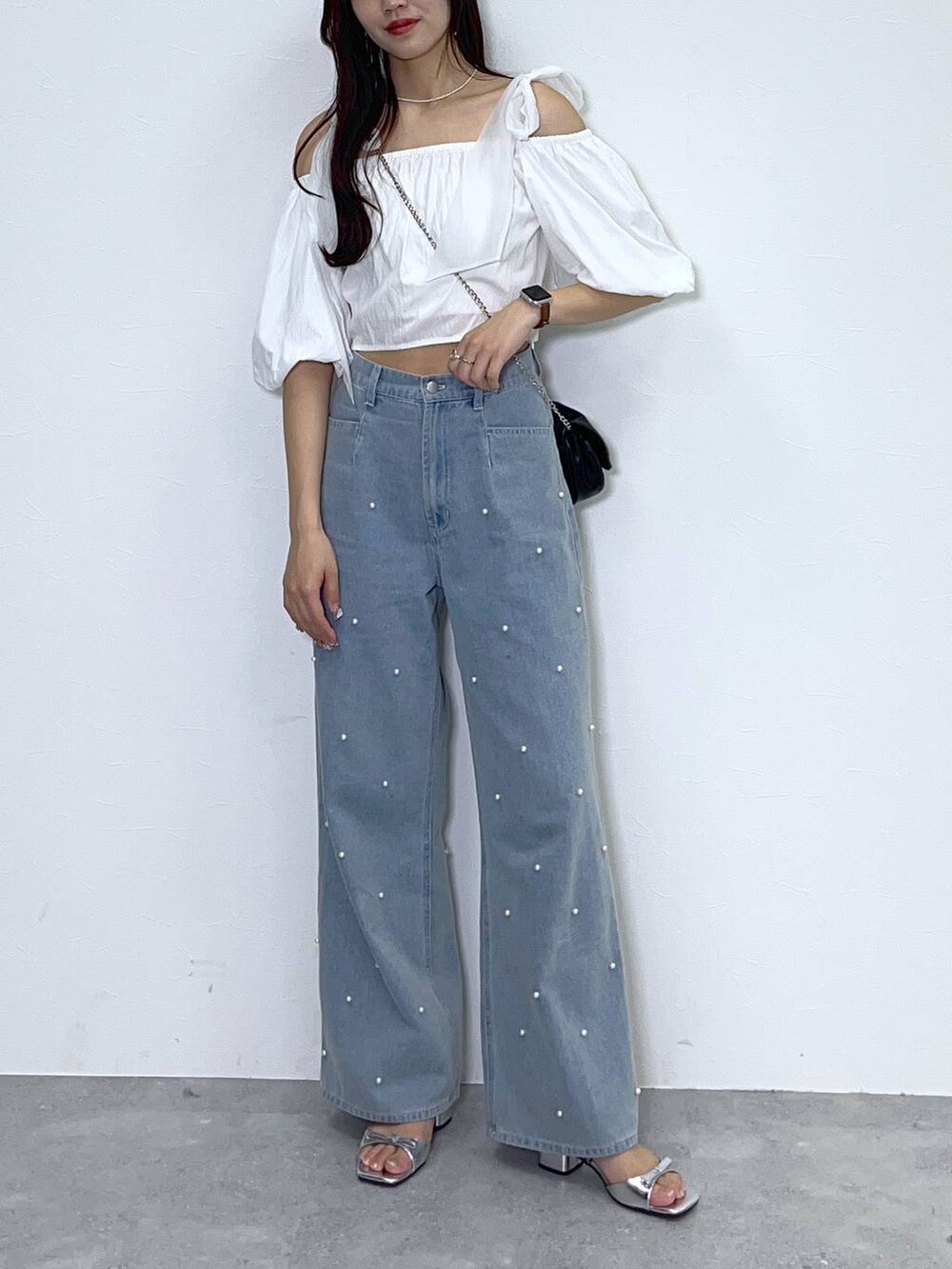 ブラック系のショルダーバッグ、ホワイト系のキャミソール、ブルー系のデニムパンツを着用したレディースの夏コーディネートの5枚目の写真