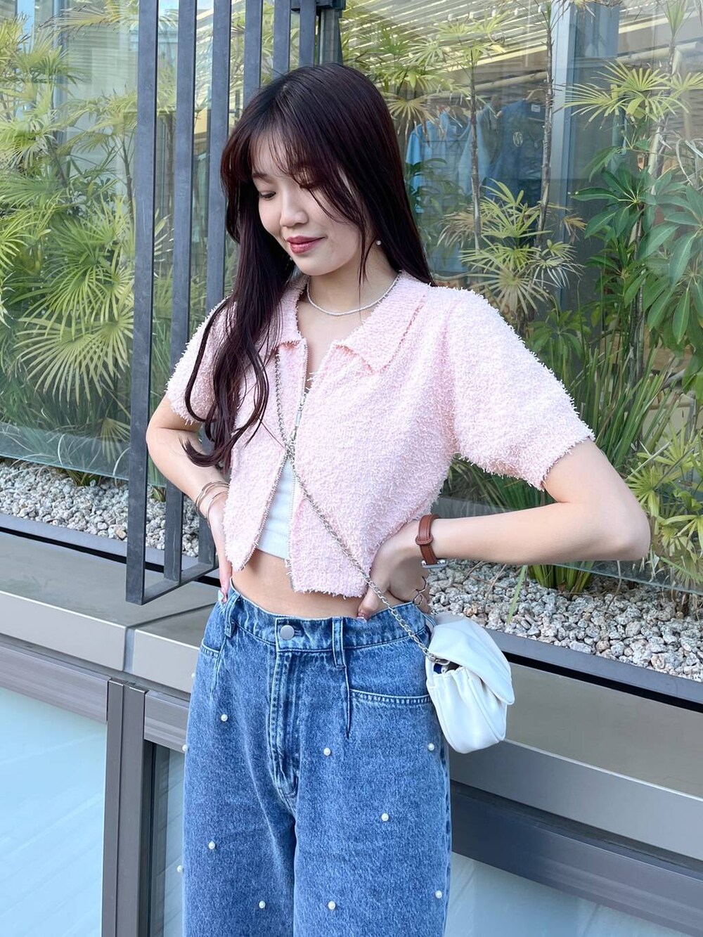 ホワイト系のショルダーバッグ、ホワイト系のキャミソール、ブルー系のデニムパンツを着用したレディースの夏コーディネートの2枚目の写真