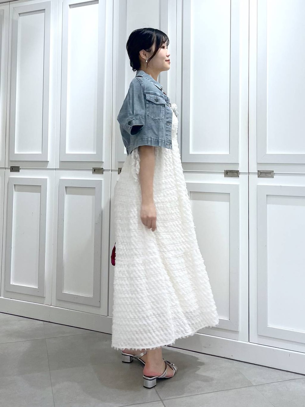 シルバー系のサンダル、ブルー系のデニムジャケット、ホワイト系のワンピースを着用したレディースの春コーディネートの6枚目の写真