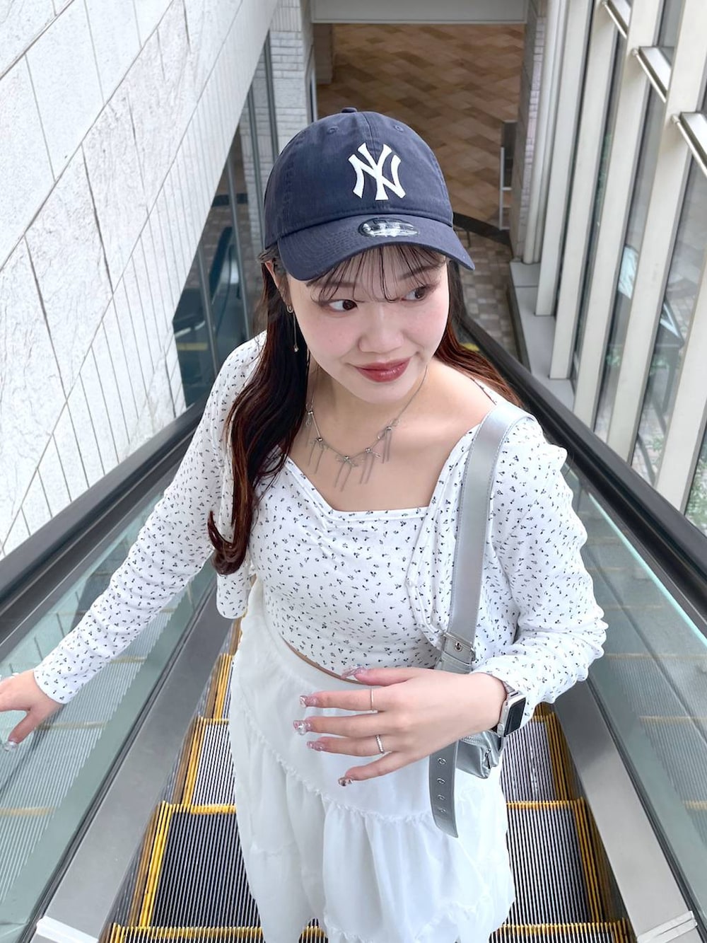 シルバー系のショルダーバッグ、ホワイト系のスカート、ホワイト系のアンサンブルを着用したレディースの春コーディネートの4枚目の写真