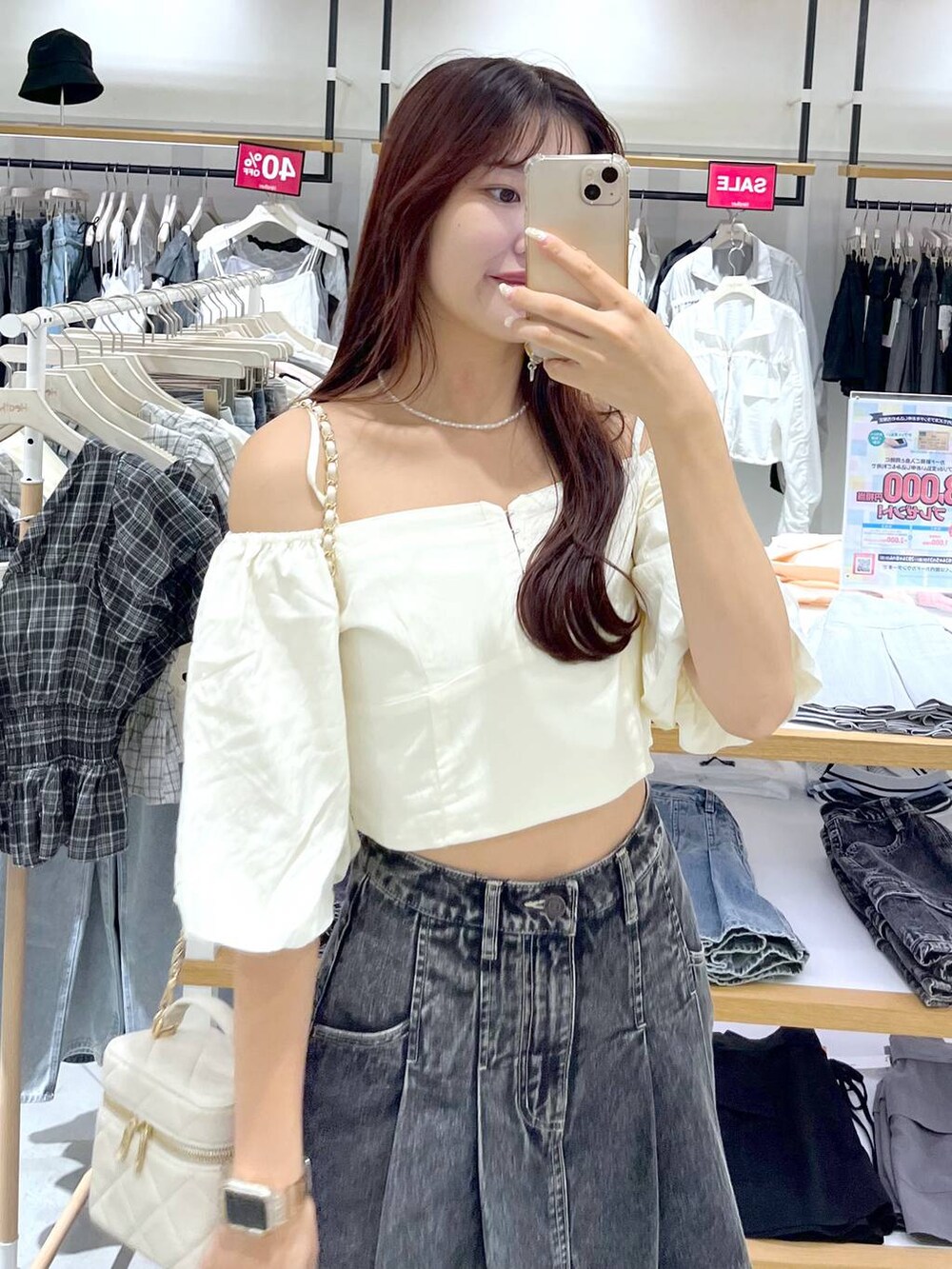 ブラック系のデニムスカート、ブラック系のサンダル、ホワイト系のショルダーバッグを着用したレディースの夏コーディネートの4枚目の写真