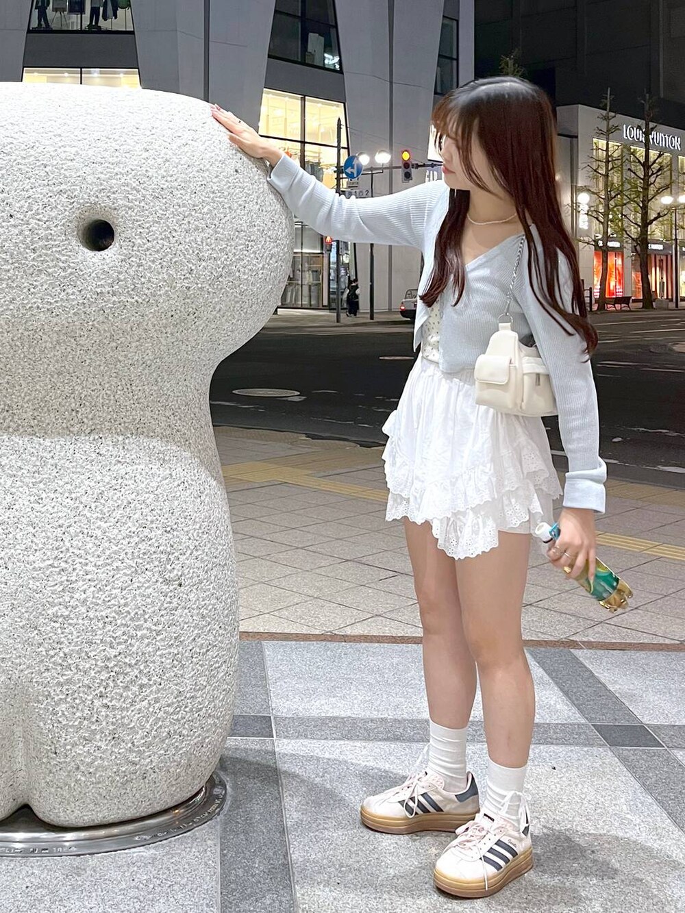 ホワイト系のキャミソール、ホワイト系のショルダーバッグ、ブルー系のカーディガン/ボレロを着用したレディースの春コーディネートの3枚目の写真