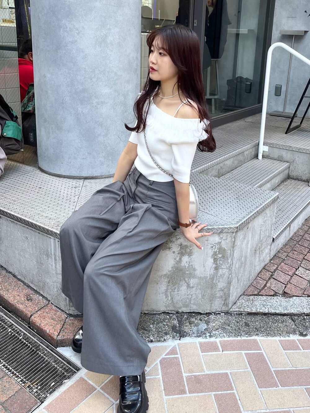 シルバー系のショルダーバッグ、ブラック系のローファー、グレー系のスラックスを着用したレディースの春コーディネートの5枚目の写真