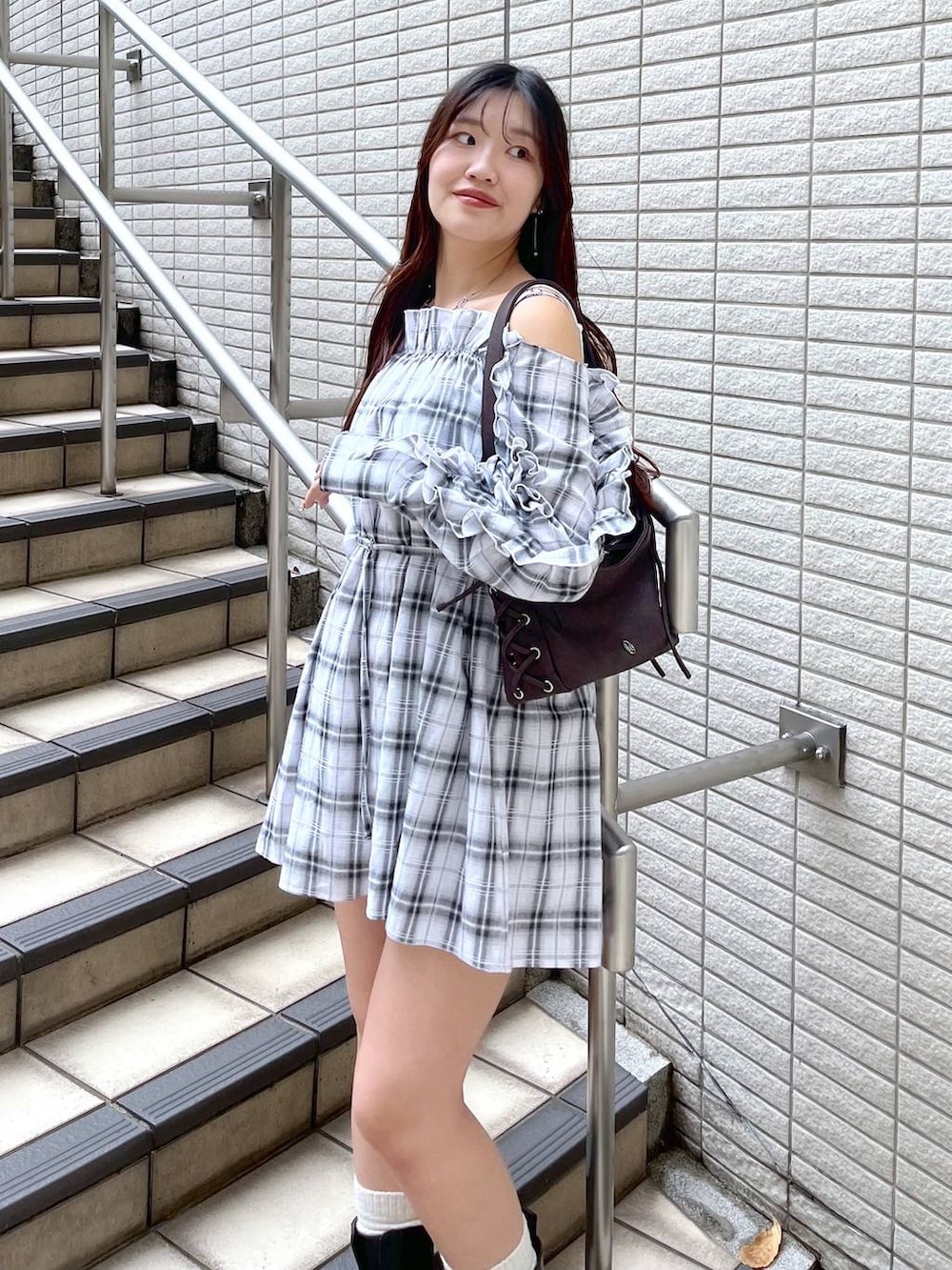 ホワイト系のキャミソール、ブラック系のデニムスカート、ブラウン系のショルダーバッグを着用したレディースの春コーディネートの3枚目の写真