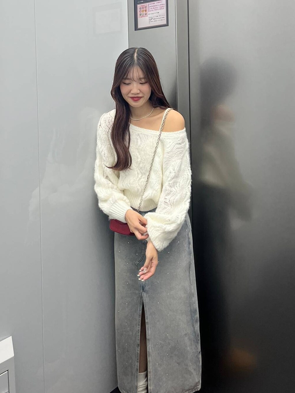 ブルー系のデニムスカート、ホワイト系のキャミソール、レッド系のショルダーバッグを着用したレディースの秋コーディネートの3枚目の写真