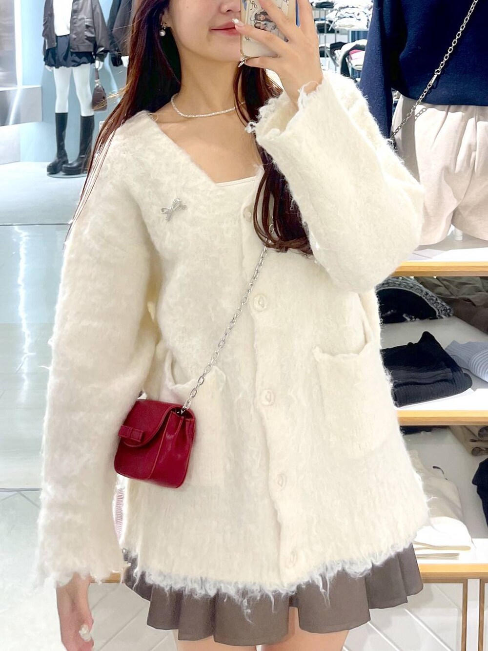 ブラウン系のスカート、ホワイト系のカーディガン/ボレロ、ベージュ系のブーツを着用したレディースの秋コーディネートの3枚目の写真