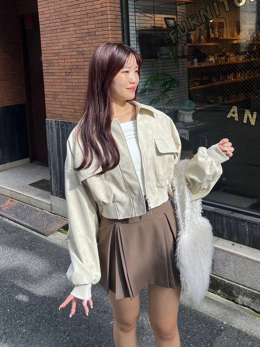 ブラウン系のスカート、ホワイト系のショルダーバッグ、ブラック系のローファーを着用したレディースの秋コーディネートの8枚目の写真