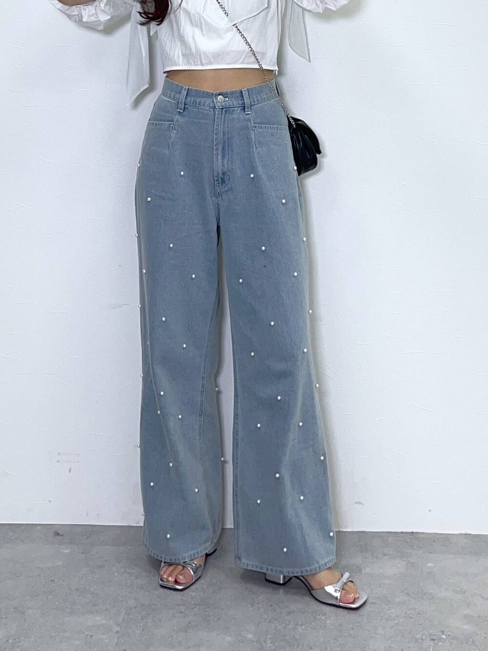 ブラック系のショルダーバッグ、ホワイト系のキャミソール、ブルー系のデニムパンツを着用したレディースの春コーディネートの7枚目の写真