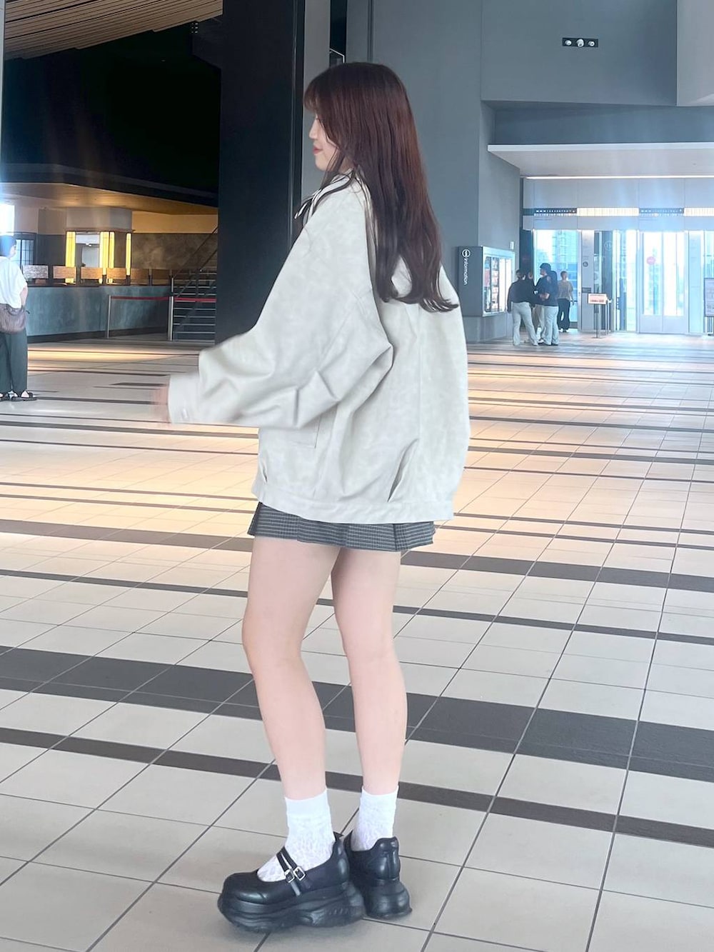 ブラック系のスニーカー、ホワイト系のキャミソール、ホワイト系のブルゾンを着用したレディースの秋コーディネートの9枚目の写真