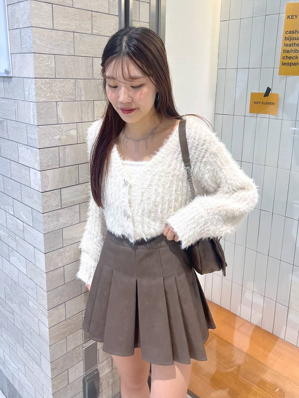 ブラウン系のショルダーバッグ、ホワイト系のアンサンブル、ホワイト系のキャミソールを着用したレディースの秋コーディネートの4枚目の写真