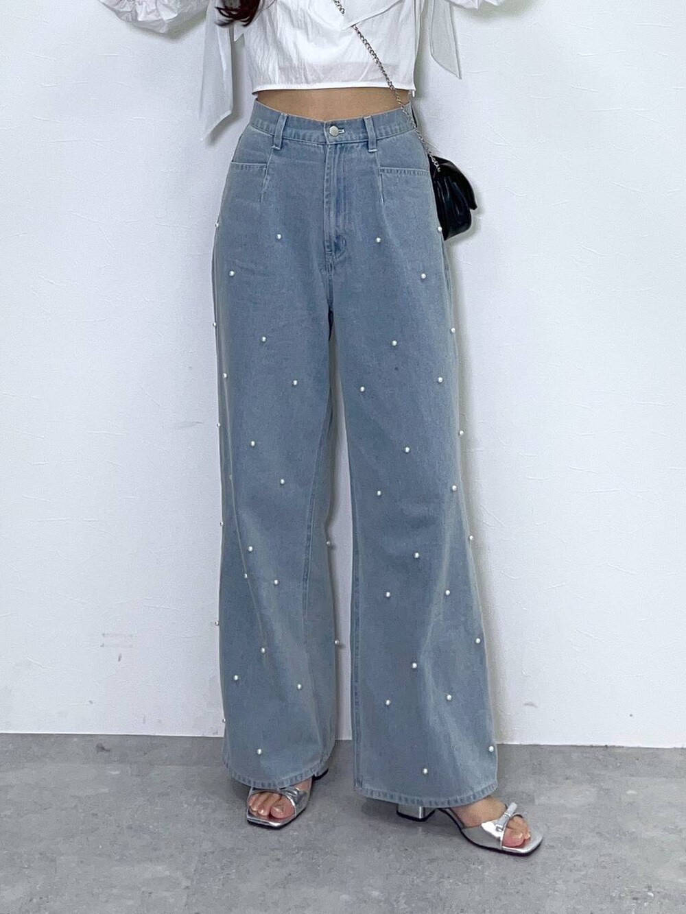 ブラック系のショルダーバッグ、ホワイト系のキャミソール、ブルー系のデニムパンツを着用したレディースの夏コーディネートの7枚目の写真