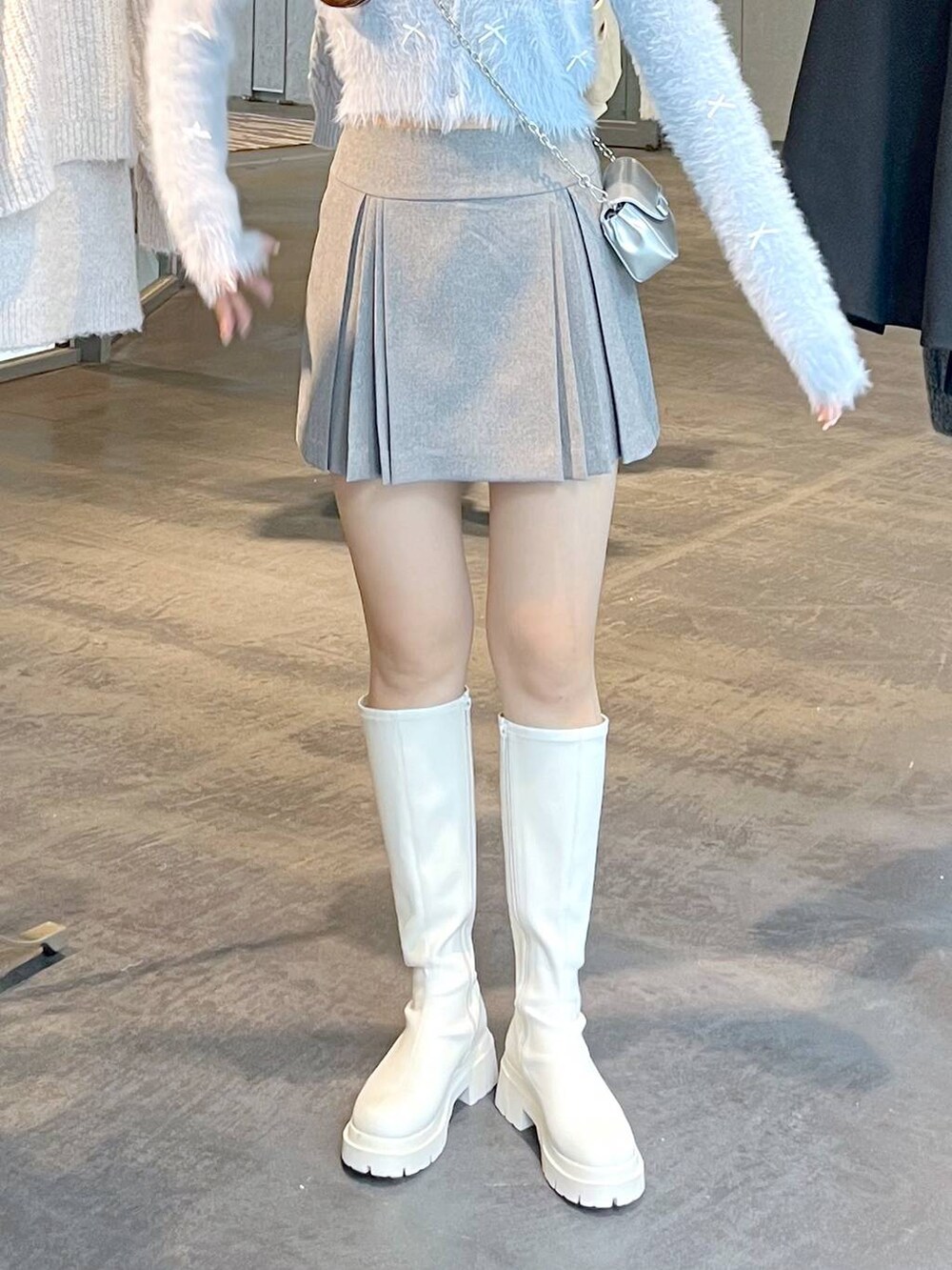 グレー系のスカート、ホワイト系のブーツ、ホワイト系のTシャツ/カットソーを着用したレディースの秋コーディネートの6枚目の写真