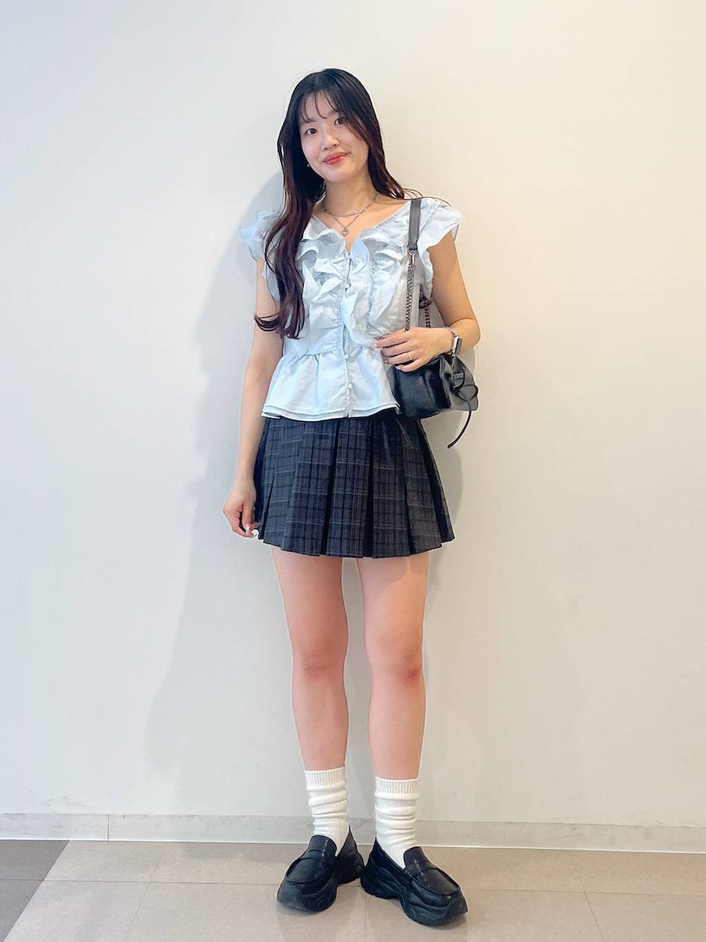 グレー系のショルダーバッグ、ホワイト系のキャミソール、ブラック系のローファーを着用したレディースの夏コーディネートの2枚目の写真