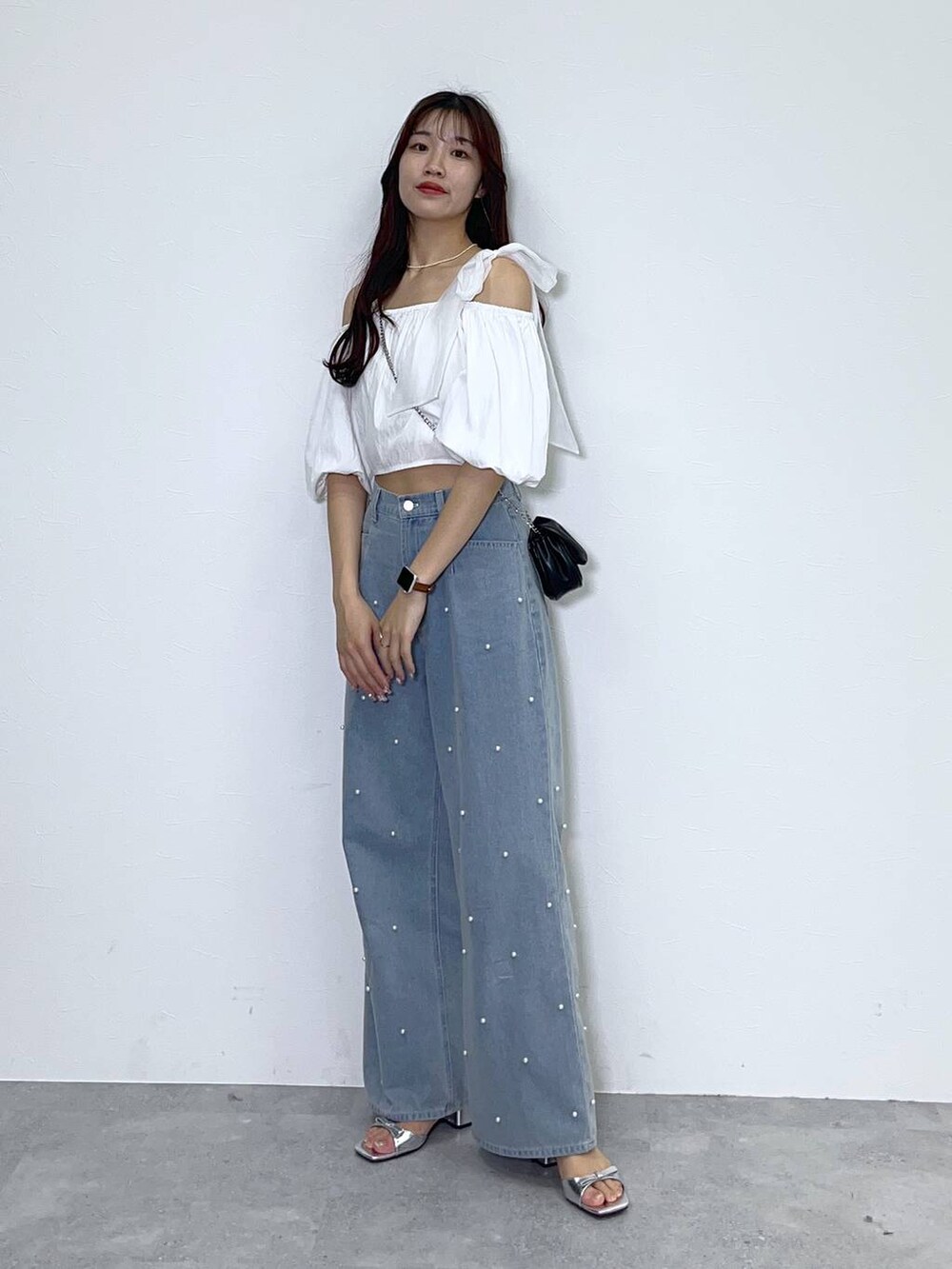 ブラック系のショルダーバッグ、ホワイト系のキャミソール、ブルー系のデニムパンツを着用したレディースの春コーディネートの5枚目の写真