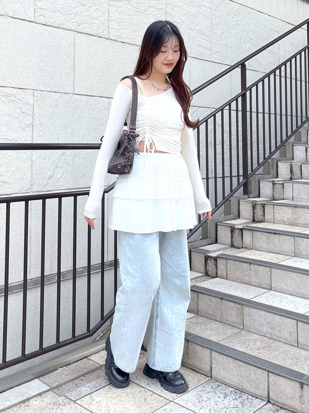 ブルー系のデニムパンツ、ホワイト系のキャミソール、ホワイト系のスカートを着用したレディースの春コーディネートの2枚目の写真