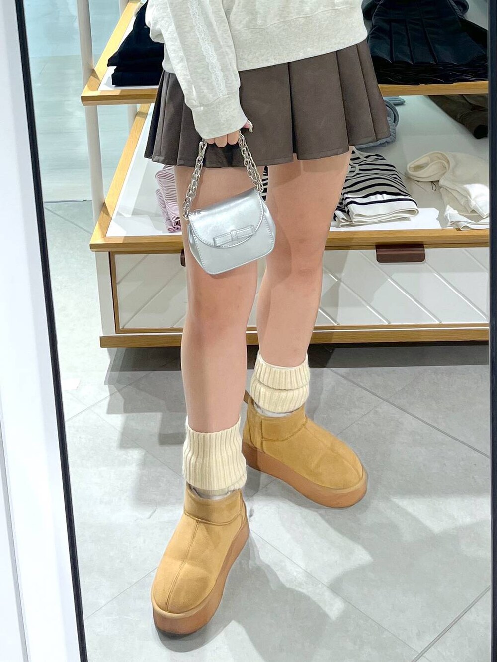 ホワイト系のTシャツ/カットソー、ブラウン系のスカート、ベージュ系のブーツを着用したレディースの秋コーディネートの7枚目の写真