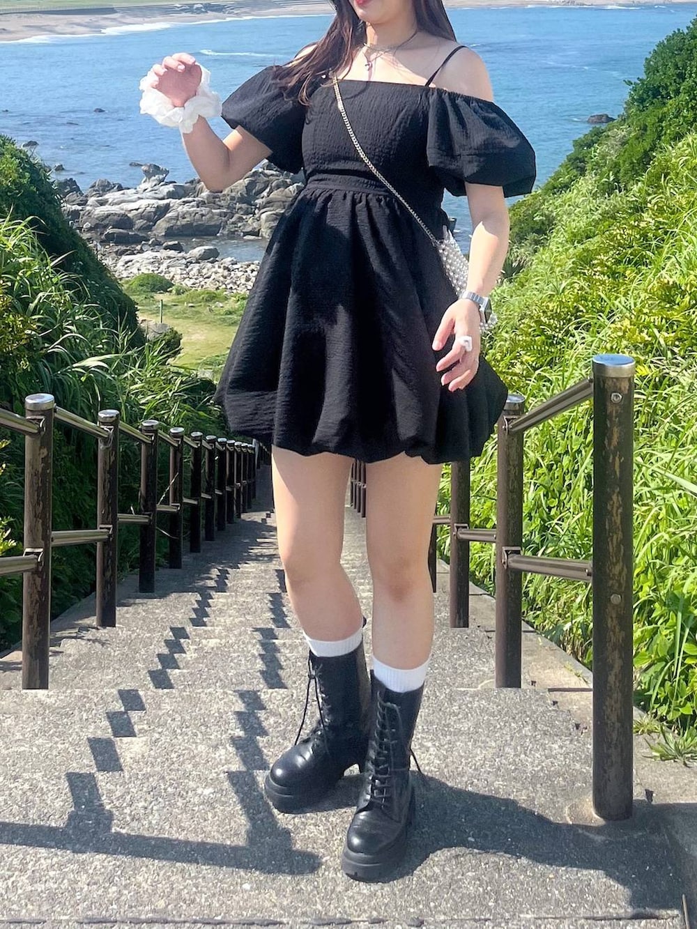 ホワイト系のキャミソール、ブラック系のワンピース、ブラック系のブーツを着用したレディースの夏コーディネートの7枚目の写真