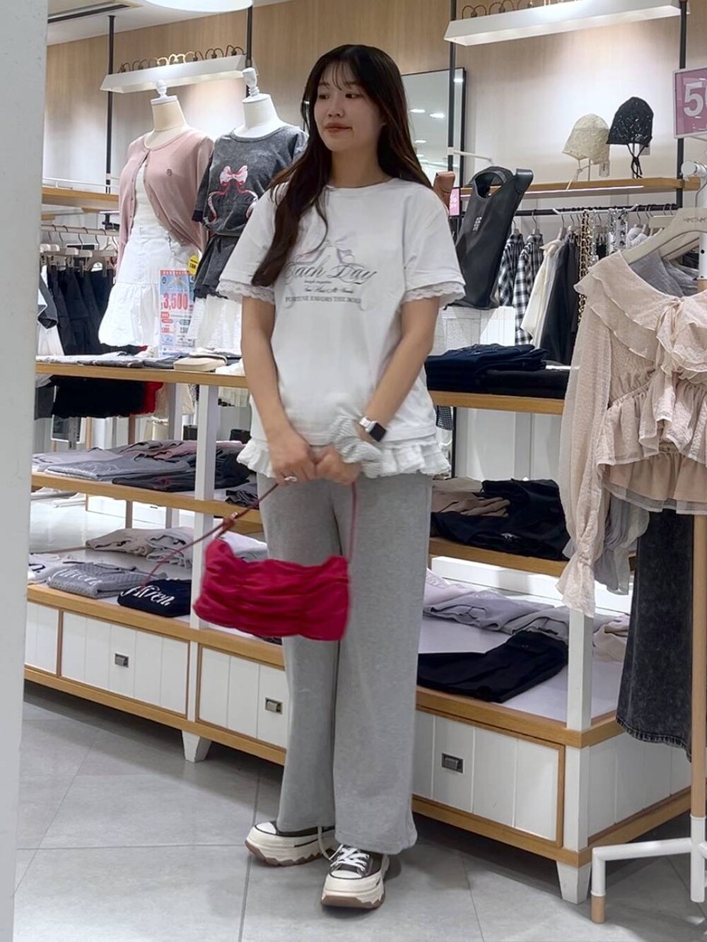 ホワイト系のキャミソール、レッド系のショルダーバッグ、グレー系のスウェットパンツを着用したレディースの春コーディネートの5枚目の写真