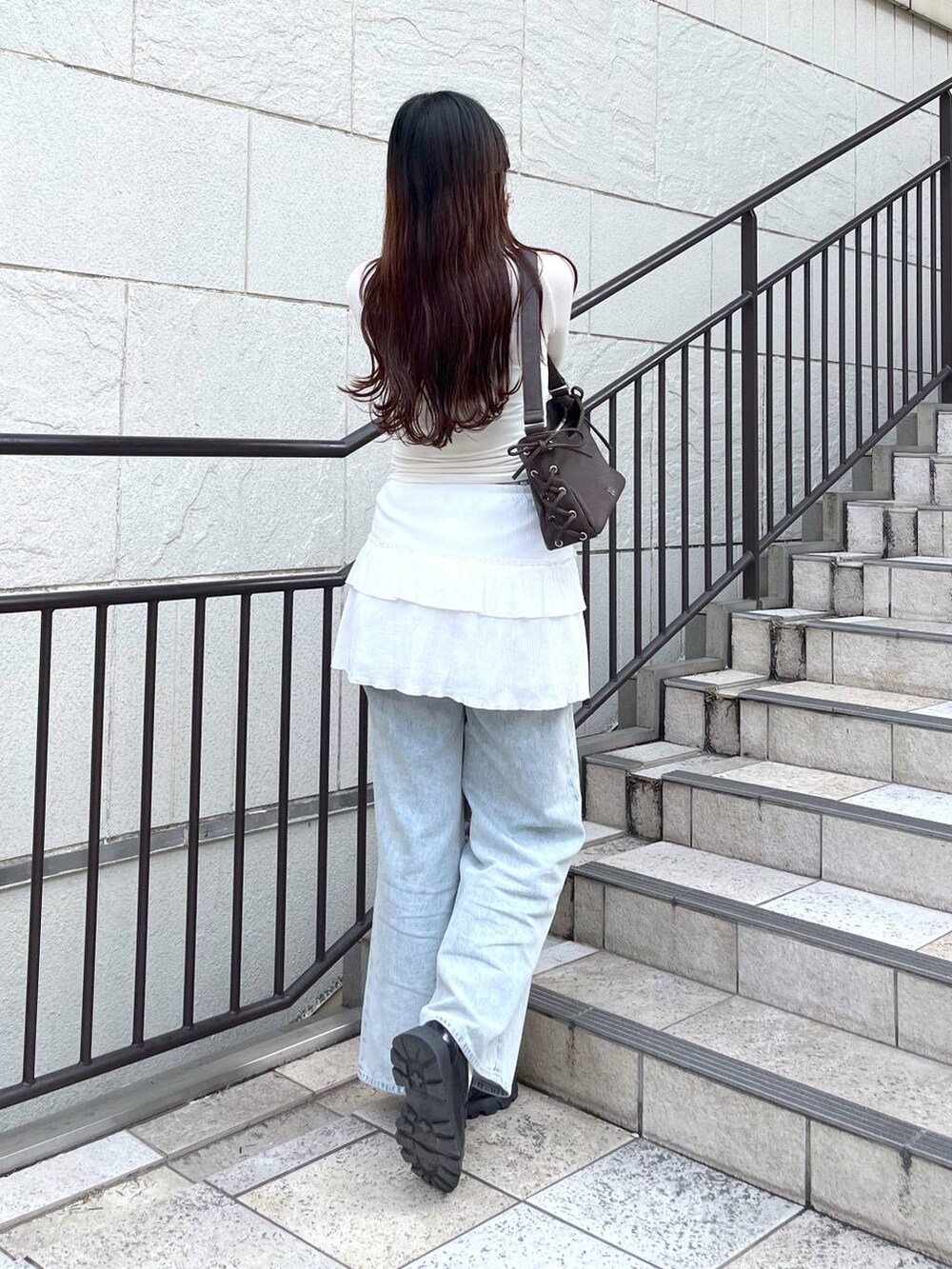 ホワイト系のキャミソール、ブルー系のデニムパンツ、ホワイト系のスカートを着用したレディースの春コーディネートの4枚目の写真