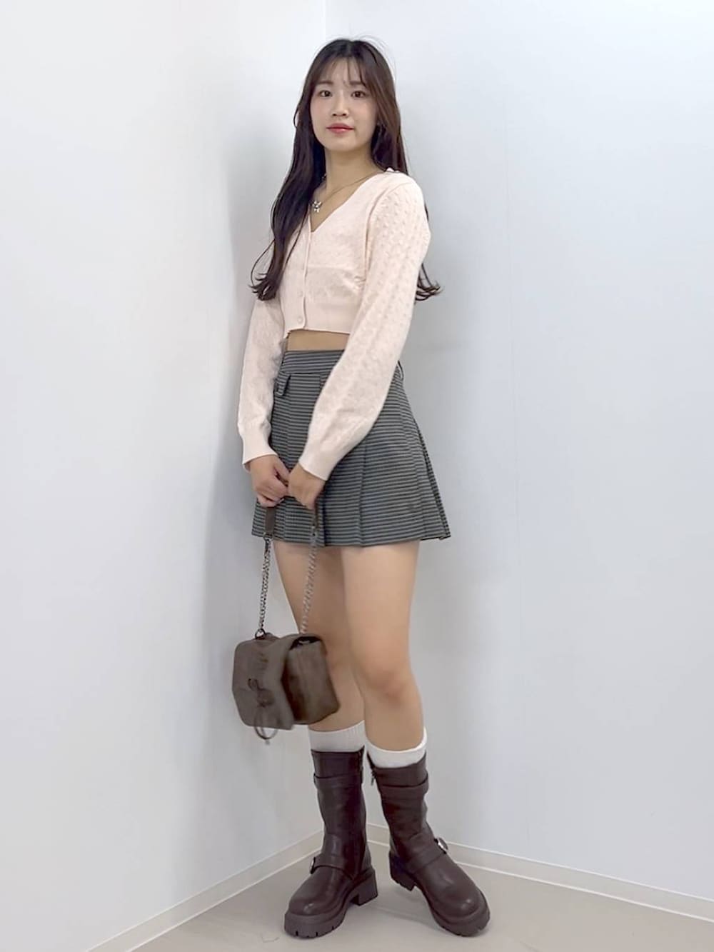 ブラウン系のショルダーバッグ、ブラウン系のブーツ、ホワイト系のキャミソールを着用したレディースの秋コーディネートの5枚目の写真