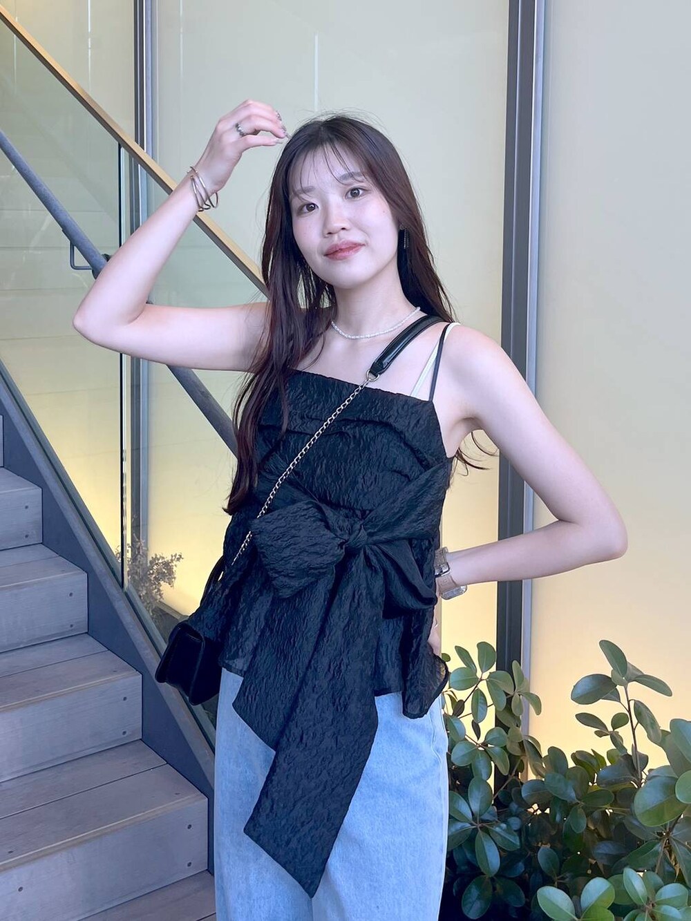 シルバー系のサンダル、ブラック系のショルダーバッグ、ホワイト系のキャミソールを着用したレディースの夏コーディネートの3枚目の写真