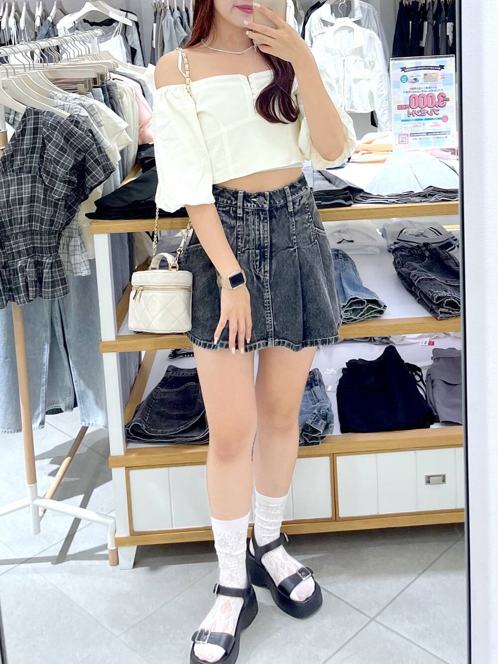 ブラック系のデニムスカート、ブラック系のサンダル、ホワイト系のショルダーバッグを着用したレディースの夏コーディネートの3枚目の写真