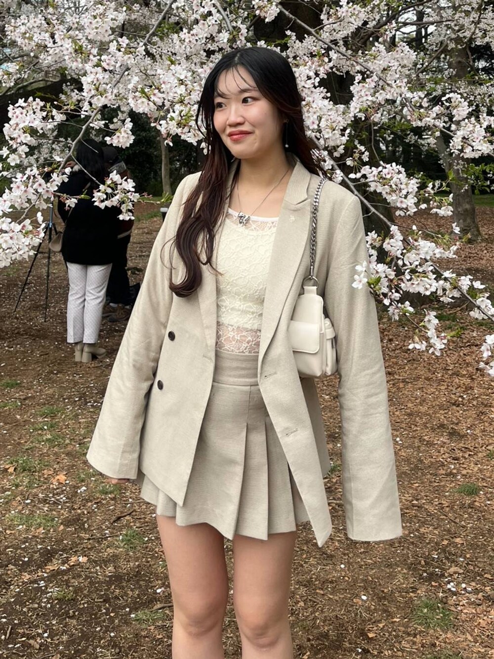 ホワイト系のキャミソール、ベージュ系のスカート、シルバー系のネックレスを着用したレディースの春コーディネートの3枚目の写真