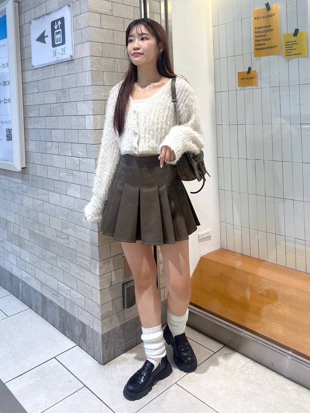 ブラウン系のショルダーバッグ、ホワイト系のアンサンブル、ホワイト系のキャミソールを着用したレディースの秋コーディネートの5枚目の写真