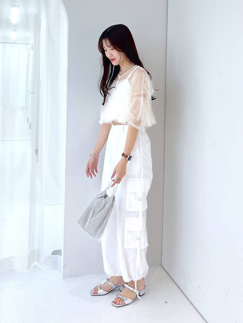 シルバー系のショルダーバッグ、ホワイト系のキャミソール、ホワイト系のベストを着用したレディースの夏コーディネートの8枚目の写真