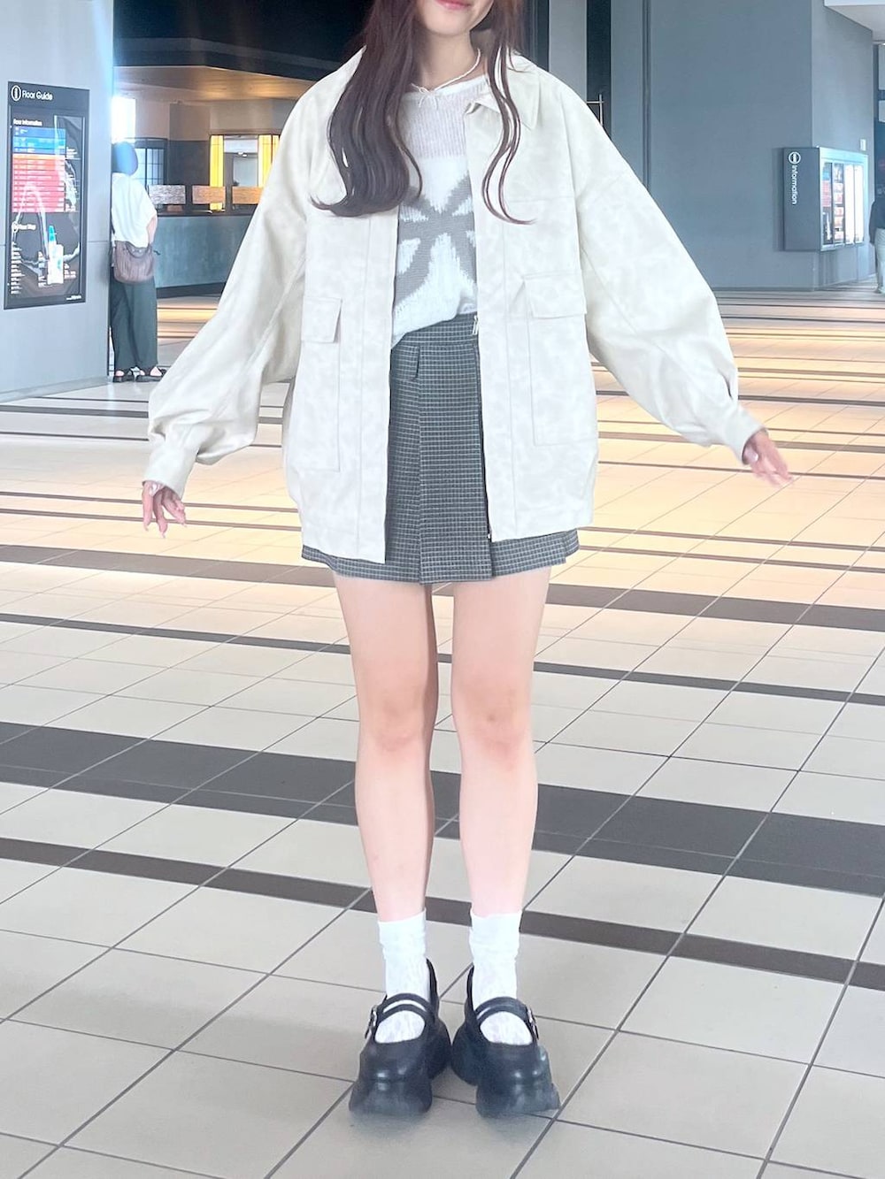 ブラック系のスニーカー、ホワイト系のキャミソール、ホワイト系のブルゾンを着用したレディースの秋コーディネートの5枚目の写真