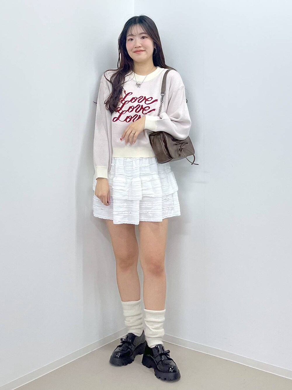 ブラウン系のショルダーバッグ、ホワイト系のTシャツ/カットソー、ホワイト系のスカートを着用したレディースの冬コーディネートの4枚目の写真