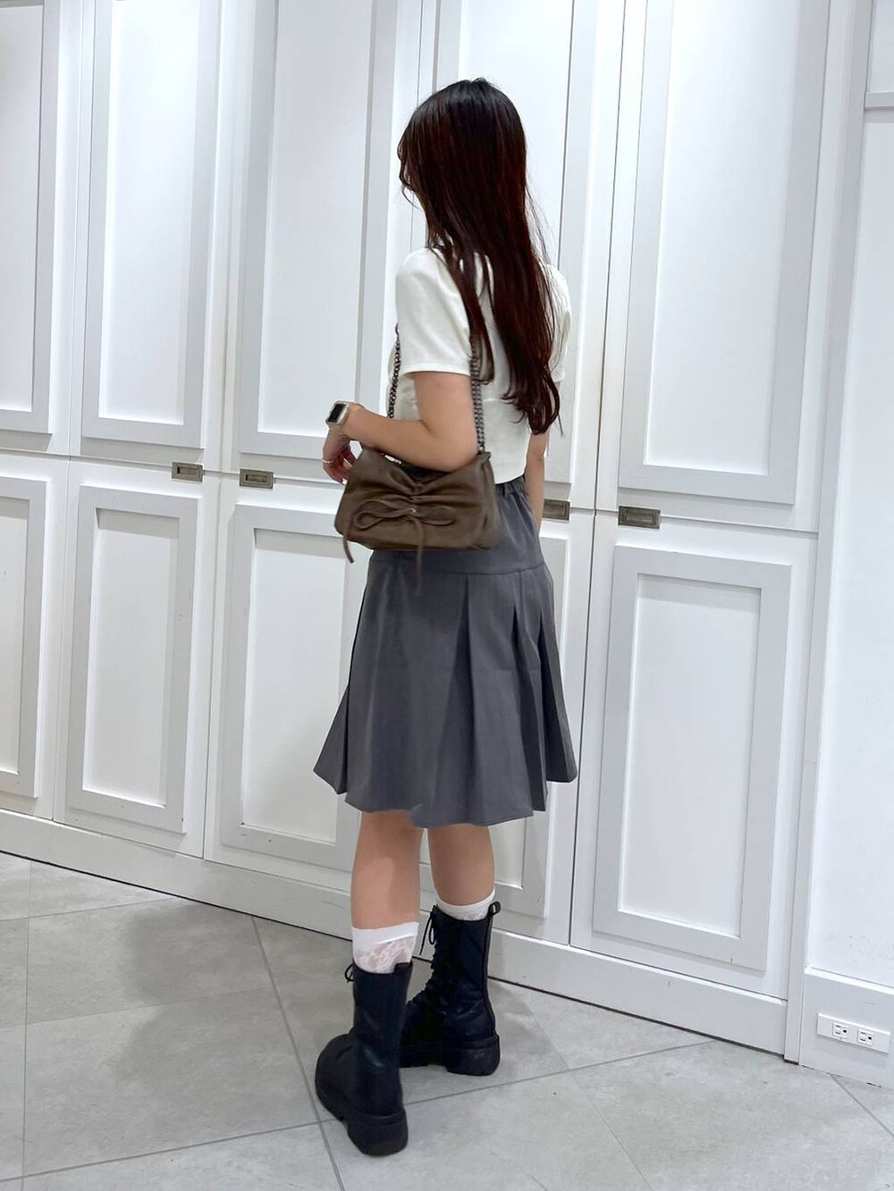 ブラウン系のショルダーバッグ、グレー系のスカート、ホワイト系のキャミソールを着用したレディースの夏コーディネートの4枚目の写真