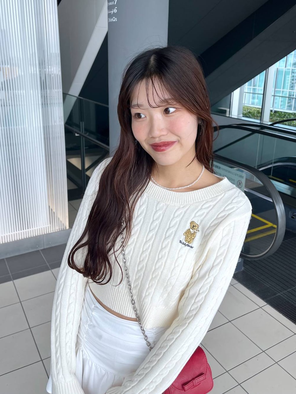 ホワイト系のTシャツ/カットソー、レッド系のショルダーバッグ、ホワイト系のブーツを着用したレディースの冬コーディネートの8枚目の写真