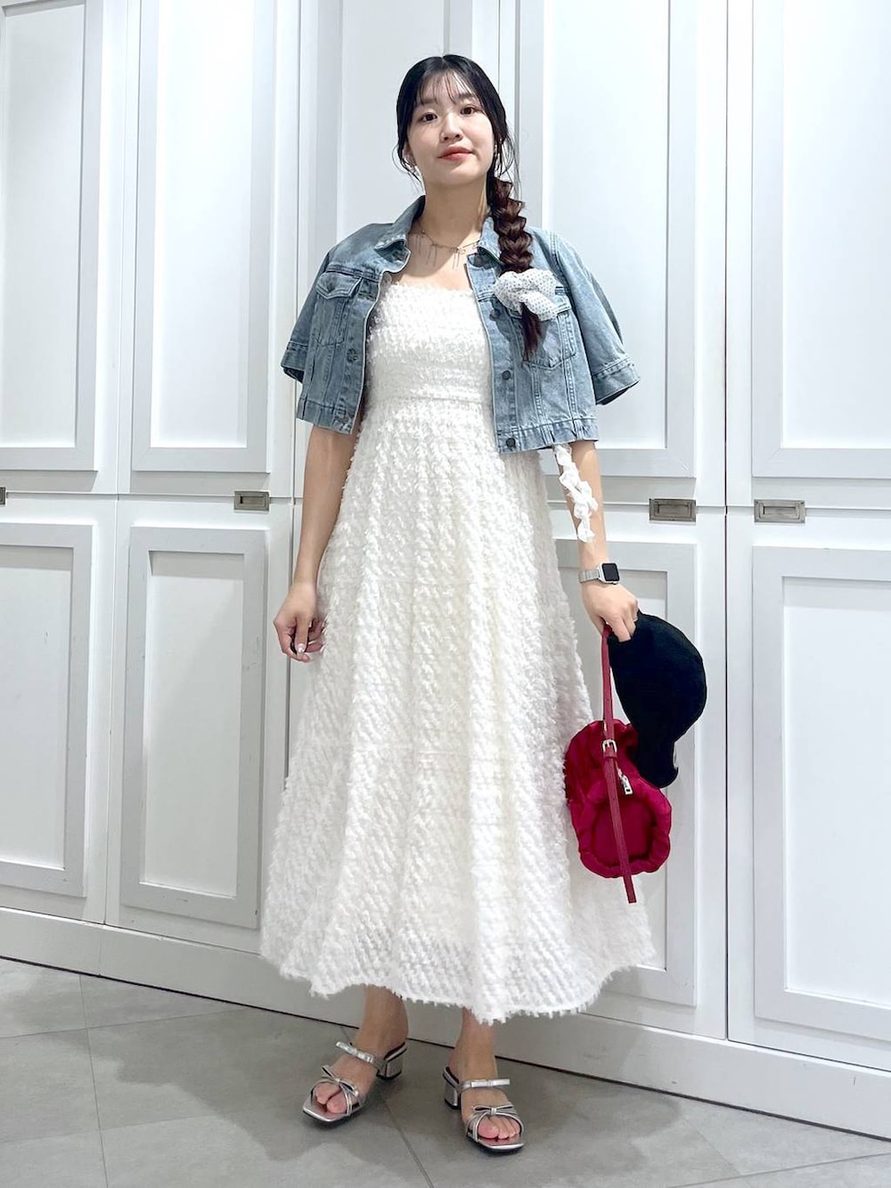 シルバー系のサンダル、ブルー系のデニムジャケット、ホワイト系のワンピースを着用したレディースの春コーディネートの3枚目の写真