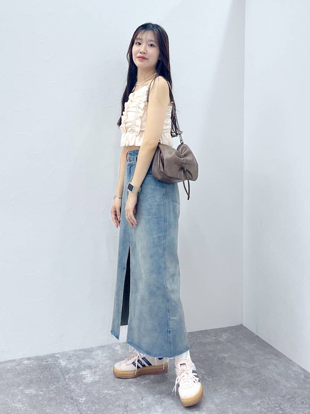 ブラウン系のショルダーバッグ、ホワイト系のキャミソール、ブルー系のデニムスカートを着用したレディースの夏コーディネートの7枚目の写真