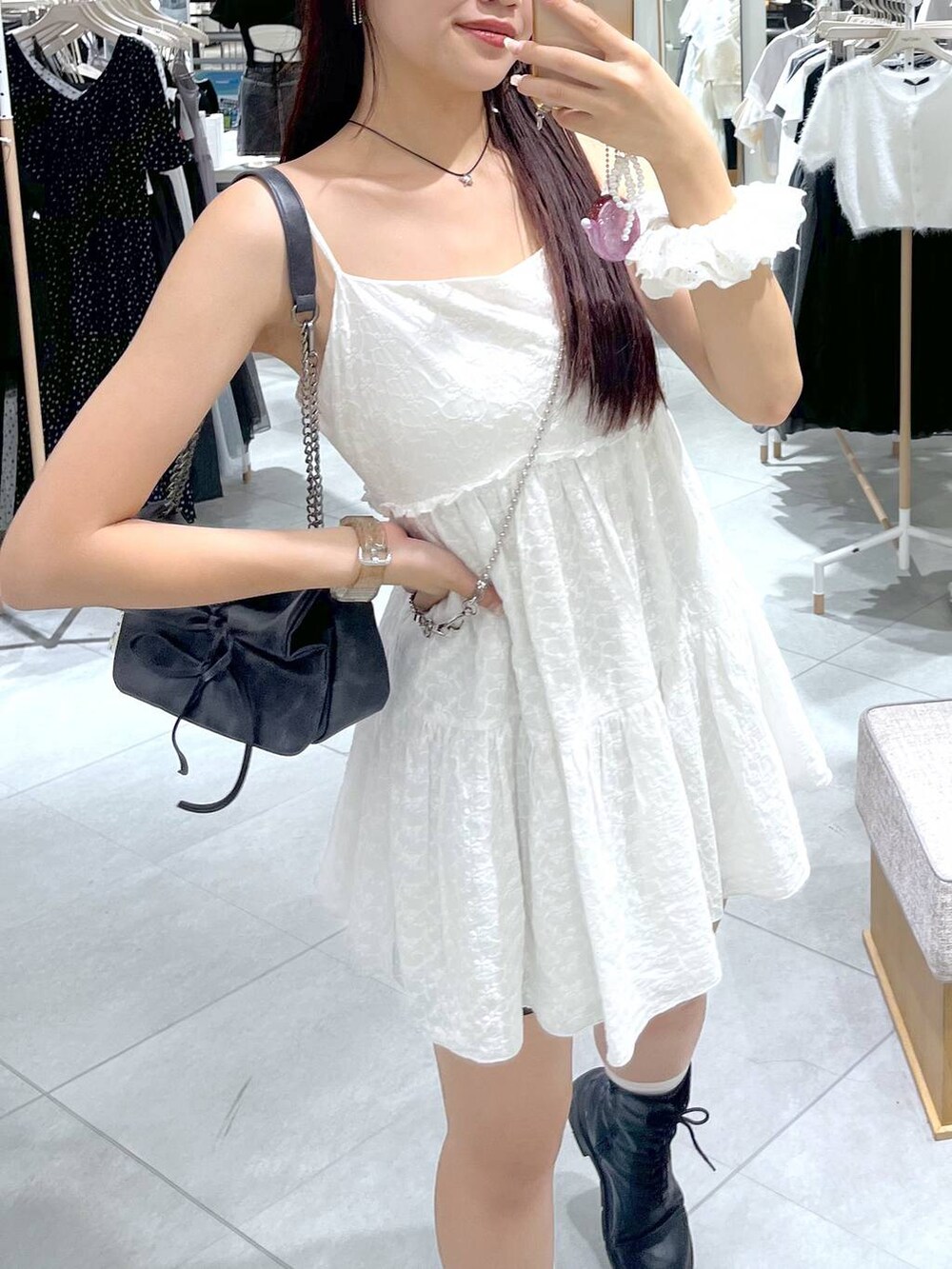 グレー系のショルダーバッグ、ホワイト系のワンピース、ブラック系のブーツを着用したレディースの夏コーディネートの4枚目の写真