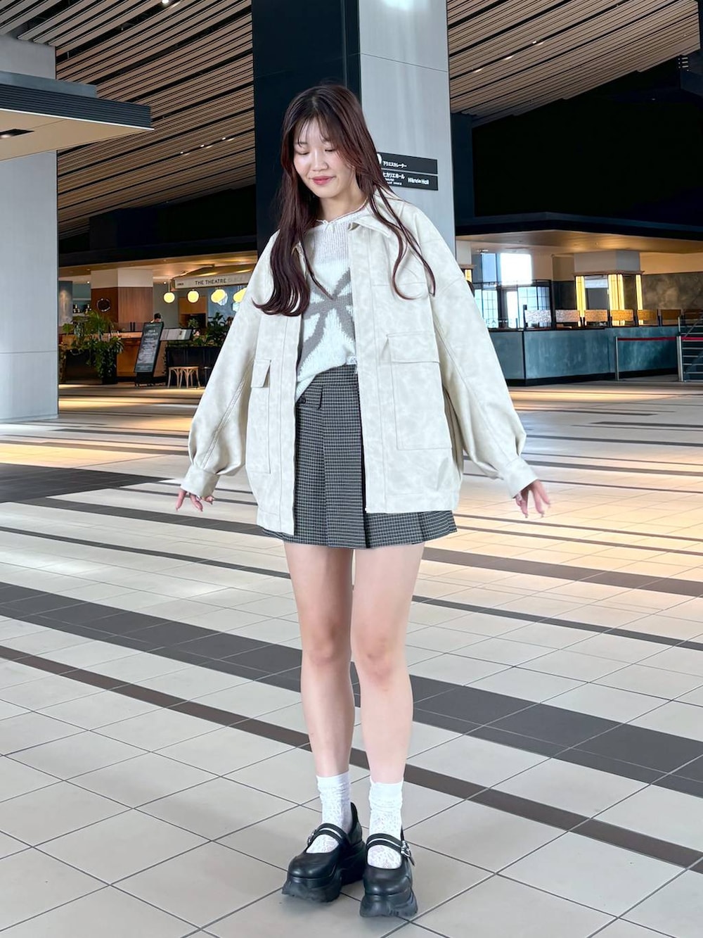 ブラック系のスニーカー、ホワイト系のキャミソール、ホワイト系のブルゾンを着用したレディースの秋コーディネートの2枚目の写真