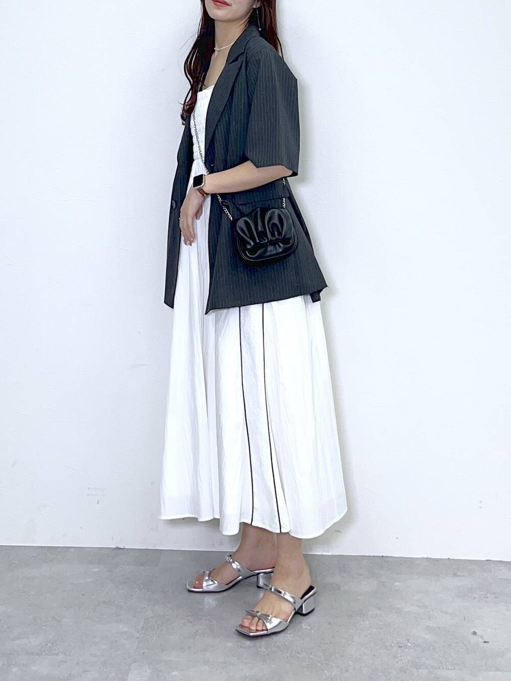 ブラック系のショルダーバッグ、シルバー系のサンダル、ホワイト系のワンピースを着用したレディースの夏コーディネートの3枚目の写真