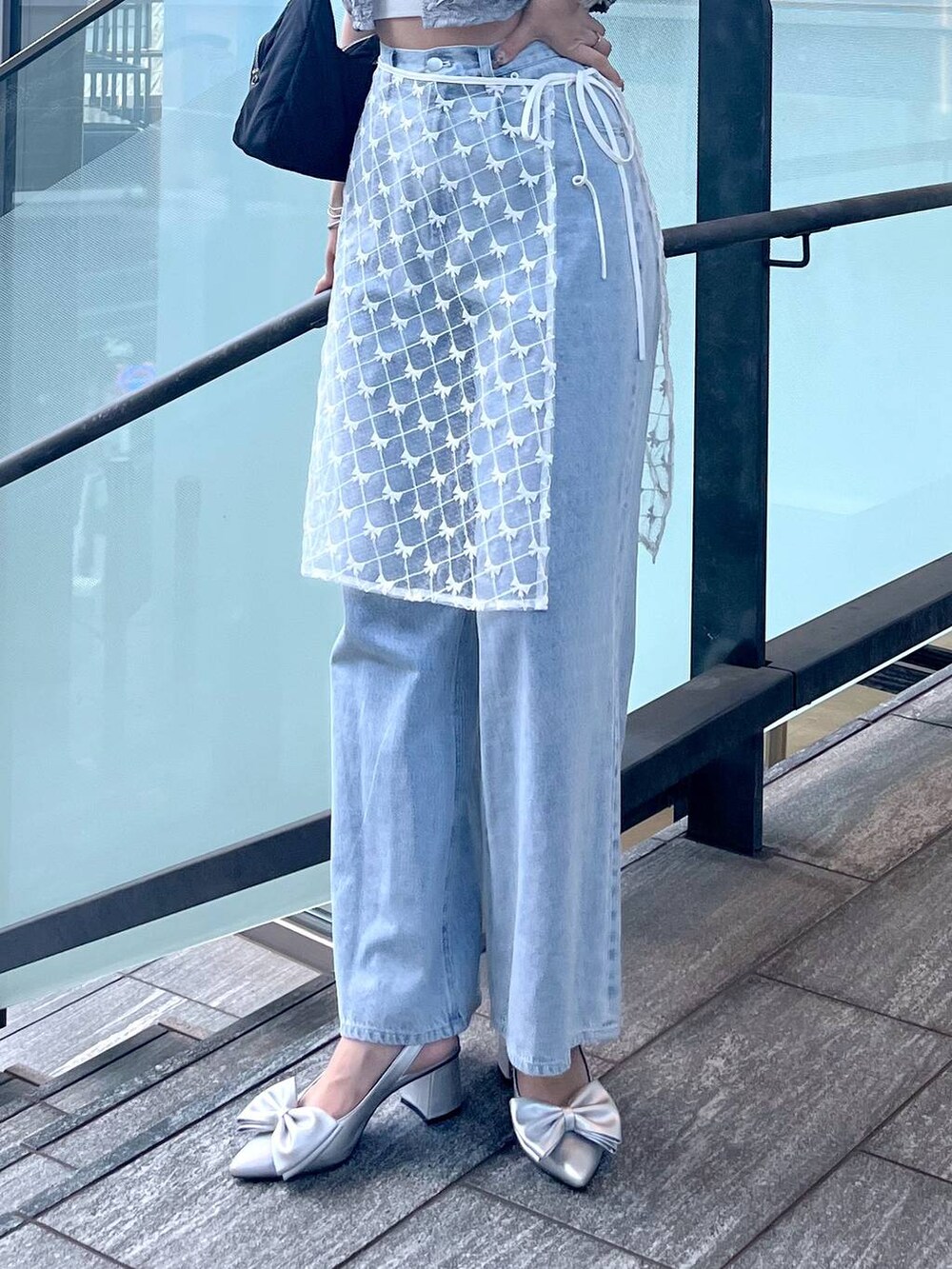 シルバー系のサンダル、ホワイト系のキャミソール、ブルー系のデニムパンツを着用したレディースの夏コーディネートの5枚目の写真