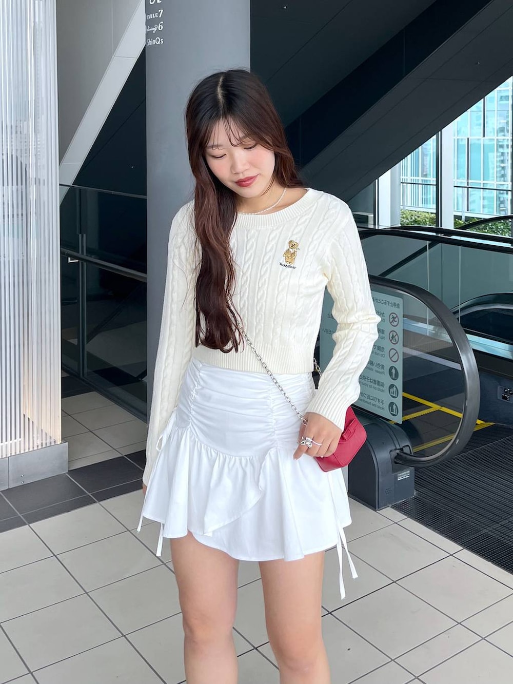 ホワイト系のTシャツ/カットソー、レッド系のショルダーバッグ、ホワイト系のブーツを着用したレディースの冬コーディネートの6枚目の写真